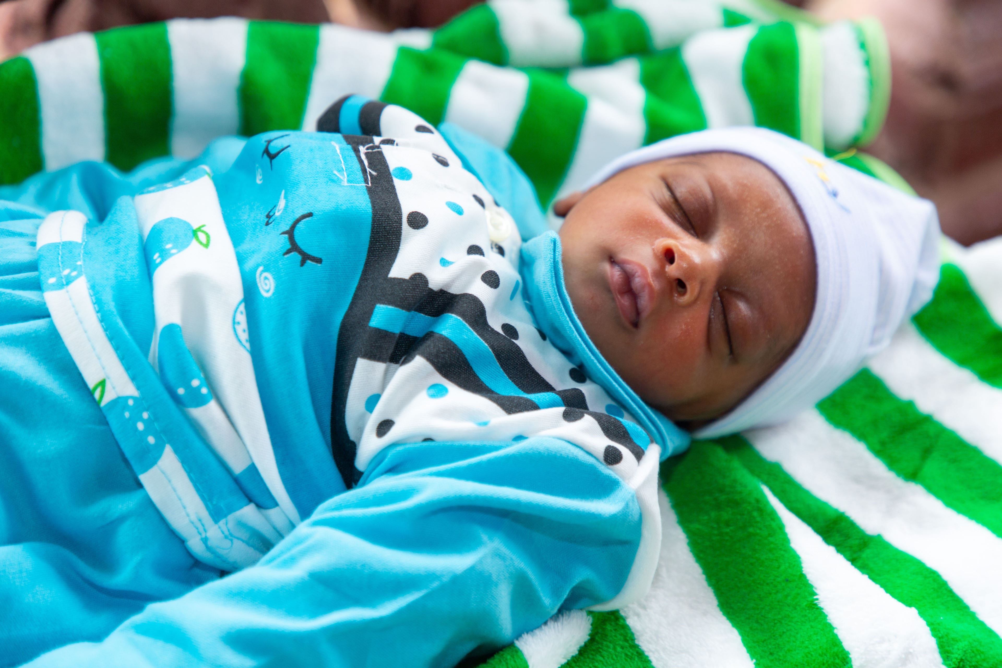 Nouveau-né endormi couché sur une couverture.