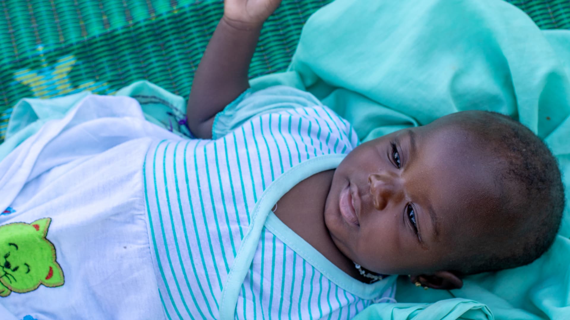 A Malian baby lies on a green blanket