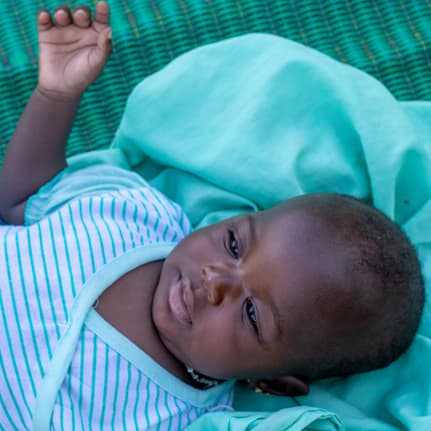 Un bébé malien est couché sur une couverture verte