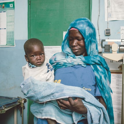 Dans un centre de santé au Burkina Faso, une mère tient son bébé dans les bras