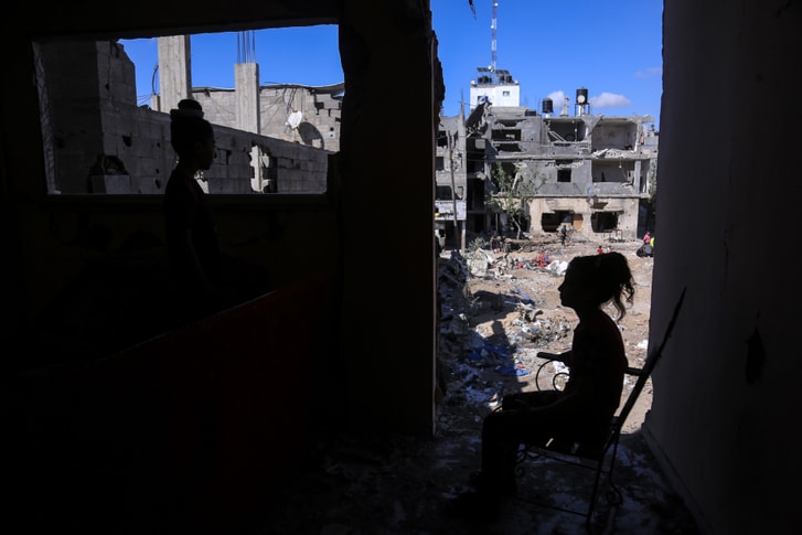 A child sitting amid destroyed buildings.